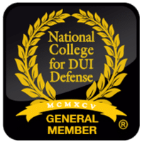 Gold laurel wreath emblem on a black rounded square background, reading 'National College for DJ Defense' with a gold ribbon and 'GENERAL MEMBER' beneath, and Roman numerals 'MCMXCV' above the ribbon.